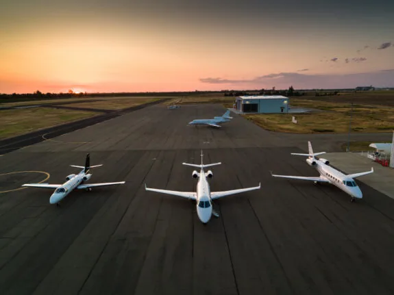 Four private jets on a runway at sunset
